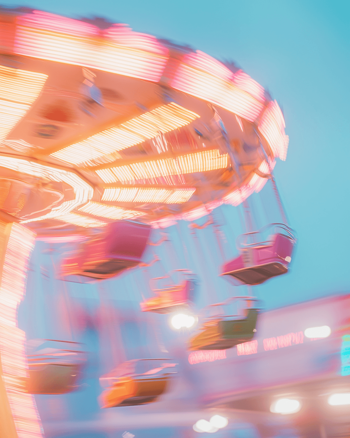Colourful fairground swing ride glowing at dusk